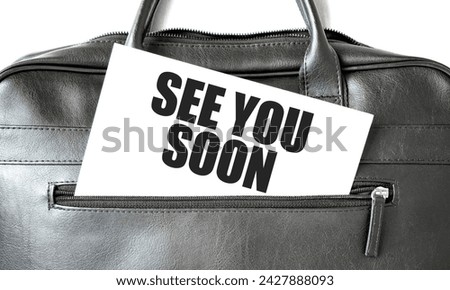 Text SEE YOU SOON writing on white paper sheet in the black business bag. Business concept