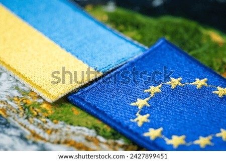 Flags of Ukraine and the European Union, patches and symbols on the background of the globe, Close up, Concept of economic cooperation and accession of Ukraine to the European Union Royalty-Free Stock Photo #2427899451