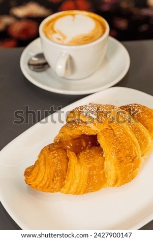 Breakfast served in an elegant bar with artisanal croissant filled with apricot jam and hot cappuccino Royalty-Free Stock Photo #2427900147