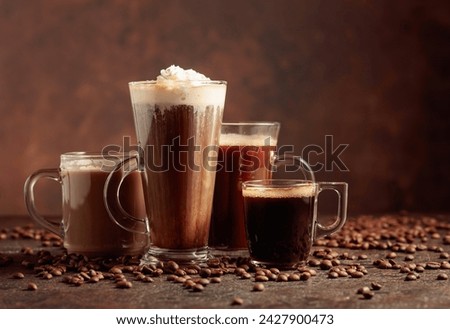 Various coffee and chocolate drinks with scattered coffee beans on a brown background. Copy space.