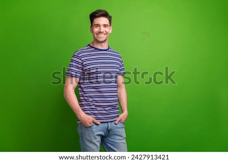 Portrait of satisfied glad young person toothy smile put hands pockets posing empty space isolated on green color background Royalty-Free Stock Photo #2427913421