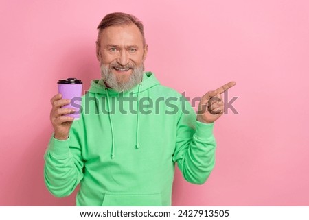 Photo of good mood excited guy dressed green hoodie enjoying coffee pointing empty space isolated pink color background
