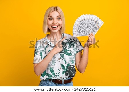 Photo portrait of lovely young lady hold money fan finger point wear trendy leaves print garment isolated on yellow color background