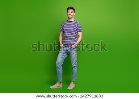 Full size photo of positive guy dressed striped t-shirt jeans trousers look at discount empty space isolated on green color background