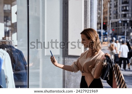 young woman taking a photo through a store window