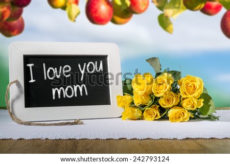 Image of a slate blackboard with message I LOVE YOU MUM and yellow roses and apples in background