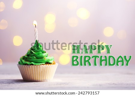 Delicious birthday cupcake on table on festive background