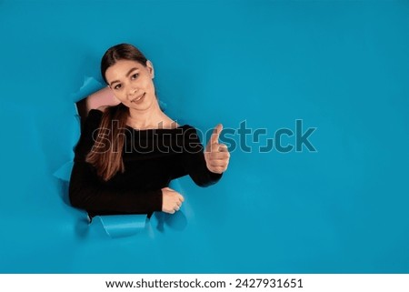 Portrait of an attractive cute lady, pointing to news, novelty, decision choice on blue background, copy space