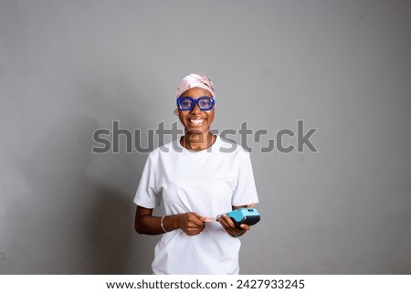 Young Woman Using her debit card holding Pos machine .paying bills online smiling