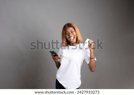 excited young lady holding her phone in an isolated grey background