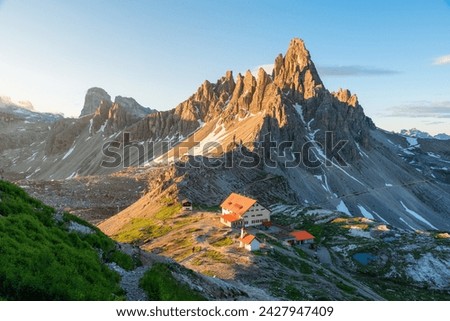 Mountain valley at the Tre Cime di Lavaredo National park and rifugio Locatelli in Dolomites Alps, Trentino Alto Adige, Italy at sunrise. Landscape with hotel for hikers, rocks and clouds Royalty-Free Stock Photo #2427947409