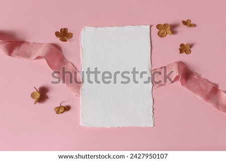 Styled stock photo. Wedding, Valentines day, birthday table composition. Stationery mockup scene. Cotton greeting card, dry hydrangea flowers and satin ribbon. Pink table background, flat lay, top 
