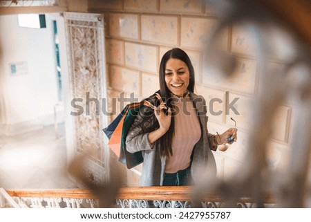 Young smiling woman climbing up staircase and being photographed through metal fence.