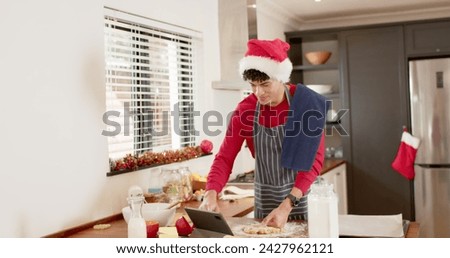 Image of frohe wihnachten text over caucasian man baking at christmas. Christmas, tradition and celebration concept digitally generated image.