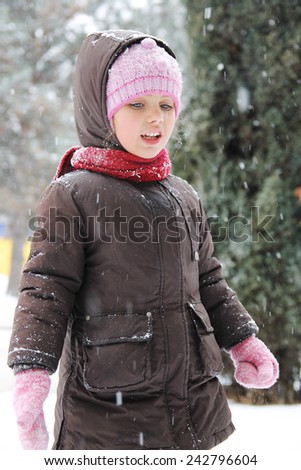 Happy girl in winter cloths enjoying snow