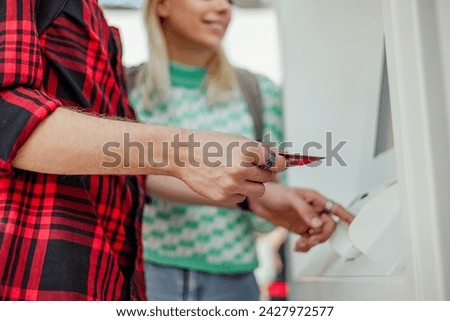 Cropped picture of hands holding credit card and typing security code on ATM. Close up of a man trying to make a transaction. Hands holding a credit card and using ATM outdoors.