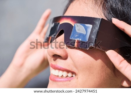Smiling young latin woman watching an eclipse of the sun with eclipse glasses Royalty-Free Stock Photo #2427974451