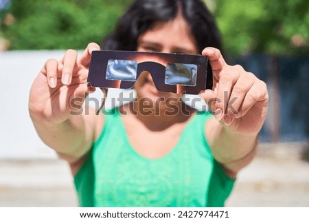 Happy young latina woman with solar eclipse glasses, watching a solar eclipse Royalty-Free Stock Photo #2427974471