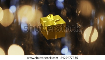 Image of gift christmas decoration over flickering spot lights on blue background. Christmas, tradition and celebration concept digitally generated image.