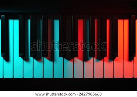 Keys of a keyboard instrument (piano, grand piano, synthesizer) shot with color lighting - blue and red light. Atmospheric music, concert, advertising of music training courses. 