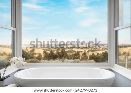 An elegant bathtub that overlooks a beautiful view of the countryside. A interior design photo of luxury living.