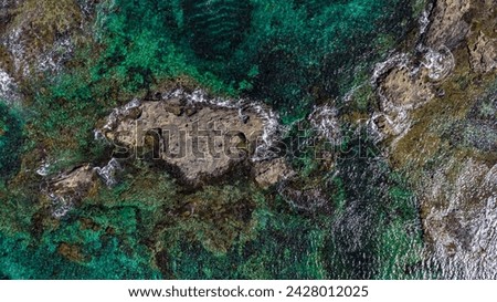 Aeriel view of rocks surrounded by greenish blue water Royalty-Free Stock Photo #2428012025