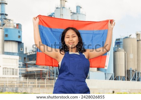Cheerful asian female worker with laotian flag standing in front of factory