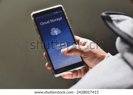 Person using his smartphone to upload and backup files to online storage or cloud storage service.