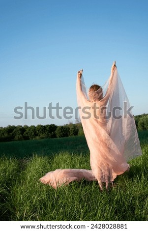 young beautiful woman stands in a field in summer with a cloth