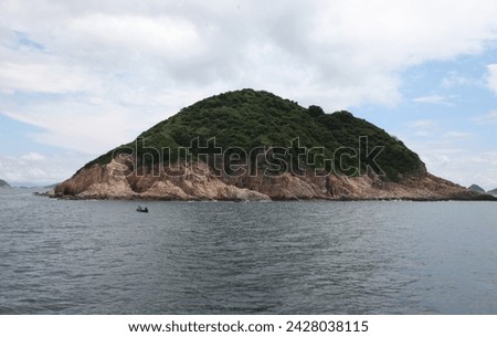 Exterior photo visual view of a natural nature ocean sea landscape with rocks island and caves with hill forest mountain on it in day time during summer nice isolated wild space with nobody on coast