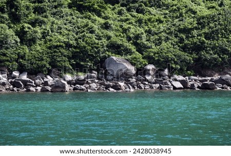 Exterior photo visual view of a natural nature ocean sea landscape with rocks island and stones with hill forest mountain on it in day time during summer nice isolated wild space with nobody on coast