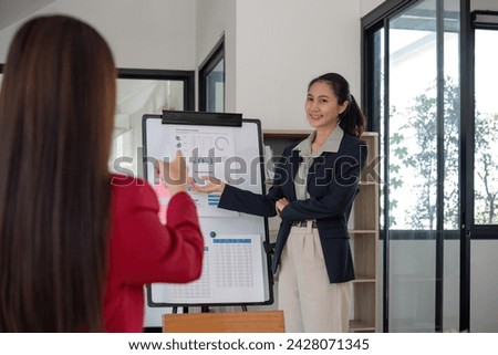 Two businesswomen discussing project strategy in office conference room Businesswoman discusses project planning with colleagues in modern workplace, gives advice on financial data report