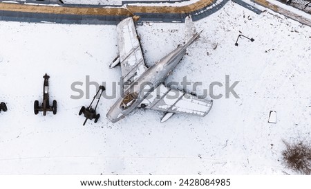 Aerial view of snow-clad tanks, artillery, armored vehicles, military vehicles, and airplanes in Poznan Citadel during winter, shot by drone.