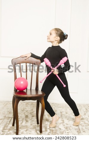 beautiful sport training rhythmic gymnastic girl with Rhythmic pink clubs doing professional exercises in white training room. standing near wooden chair 