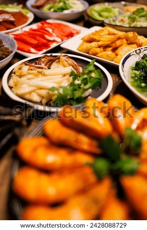 a table full of sumptuous food, including golden grilled squid, Royalty-Free Stock Photo #2428088729