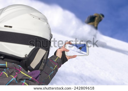 A young girl by mobile phone photographed of Snowboard freerider in the mountains
