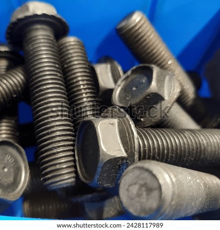 Close-up of metric screws, in burnished steel, in a blue plastic tray. Royalty-Free Stock Photo #2428117989