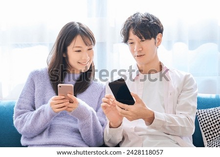 A man and a woman looking at smartphones in the room