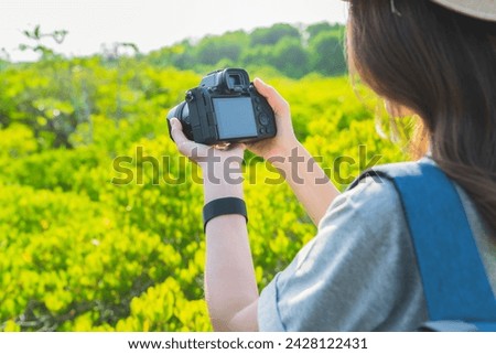 Woman tourist holding digital camera with taking photo on garden park.