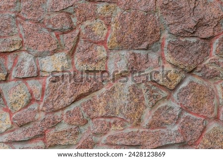 It's the close up view of red and the yellow stones of wall. This is photo of pink stone wall of building. It is view of  stone wall of castle. It is view of stone wall texture.