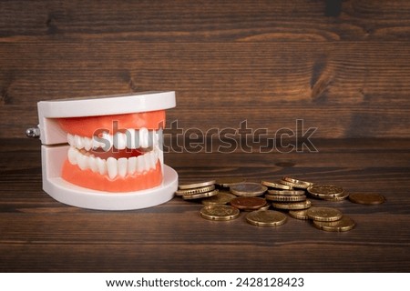 Teeth model and money on a wood texture background. Health and wellness.