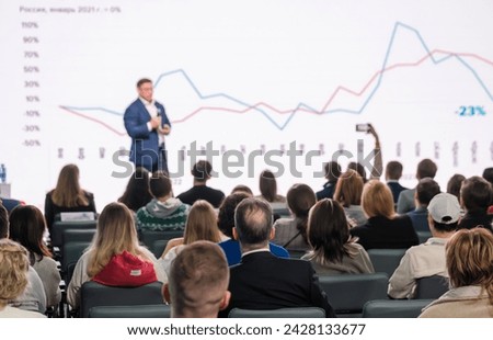 Businessman presenting growth charts to an audience at a conference event, depicting professional training.