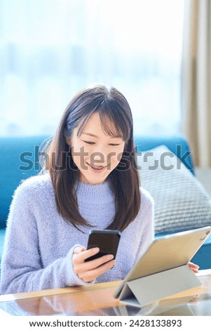 A woman comparing the screens of her smartphone and tablet PC