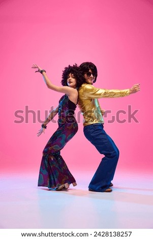 Energetic disco dance lift, couple in 1970s fashion outfit dancing in motion with playful energy against gradient pink studio background. Concept of American culture, 1970s, 1980s fashion, music, art