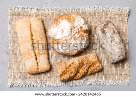 Assortment of freshly baked bread with napkin on rustic table top view. Healthy unleavened bread. French bread. Royalty-Free Stock Photo #2428142465