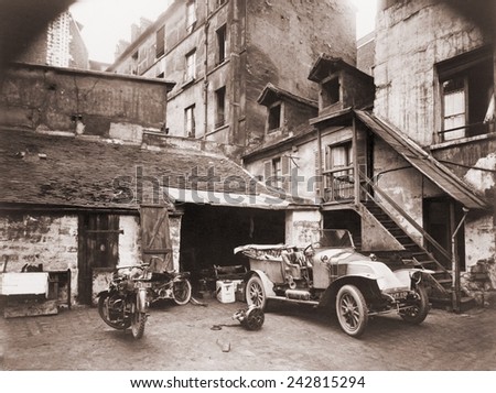Automobile and two motorcycles in courtyard on Rue de Valence, Paris, photographed by Eugene Atget with a large-format wooden bellows camera. Ca. 1920.