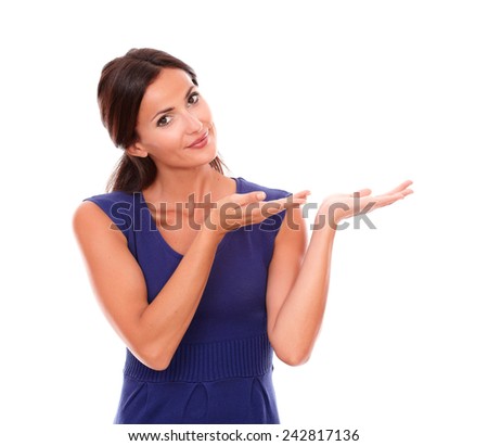 Attractive female in purple dress holding palm up while looking at you smiling in white background - copyspace