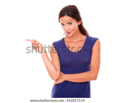 Lovely latin lady pointing to her right smiling while looking at you in white background - copyspace