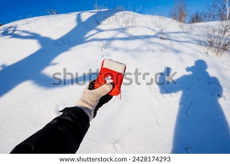 Hiker holding first aid kit in hand on background of his shadow in the snow, safety concept on hiking, mountain adventure alone. High quality photo