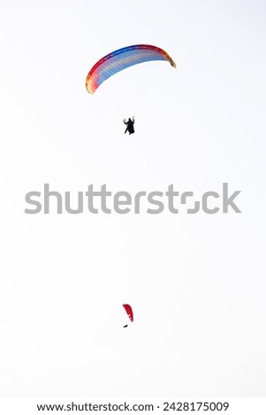 Two parachutes on white sky background. Paragliding activity in Fethiye Ölüdeniz. Extreme sports idea concept. Vertical photo. Metaphorical meaning of freedom.